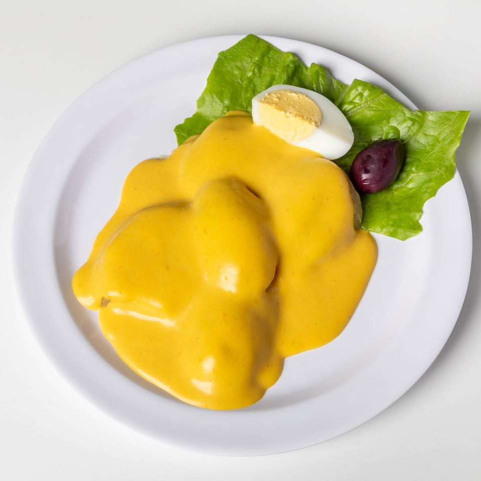 Peruvian Papa a la Huancaina, yellow sauce over potatoes, with lettuce, hard-boiled egg, and olive.