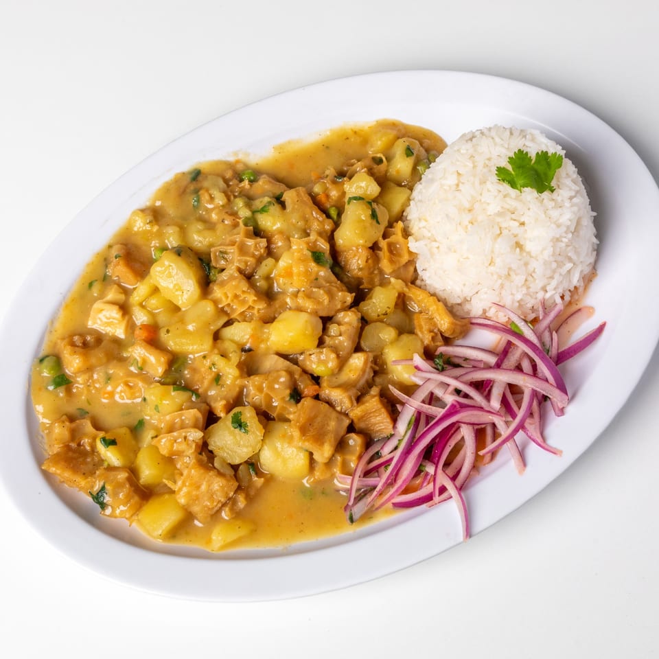 Peruvian cau cau, a tripe and potato stew in a yellow sauce, served with white rice and red onions.